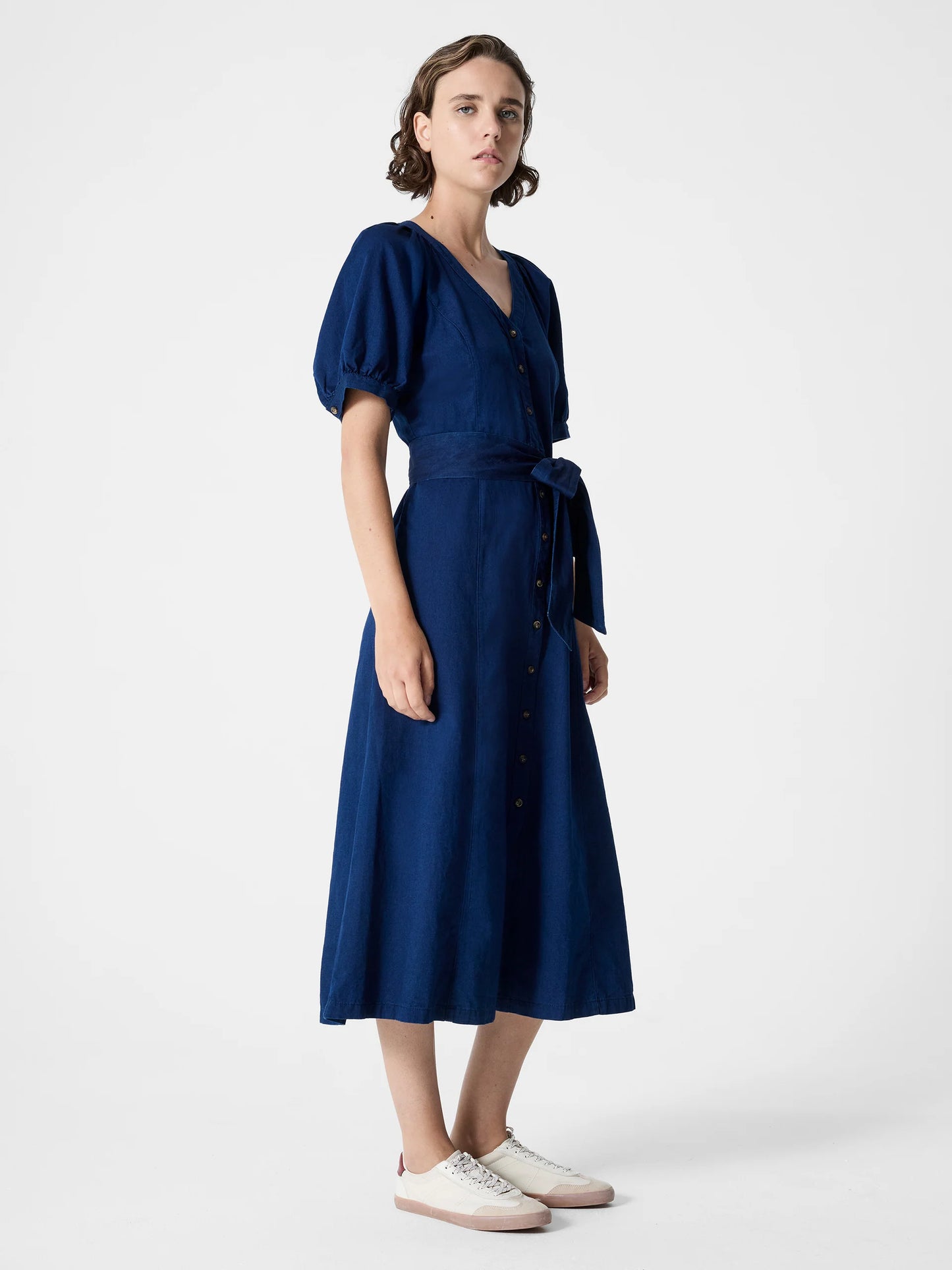 Woman wearing a dark blue maxi button through dress with V -Neck, short sleeves and tie waist.