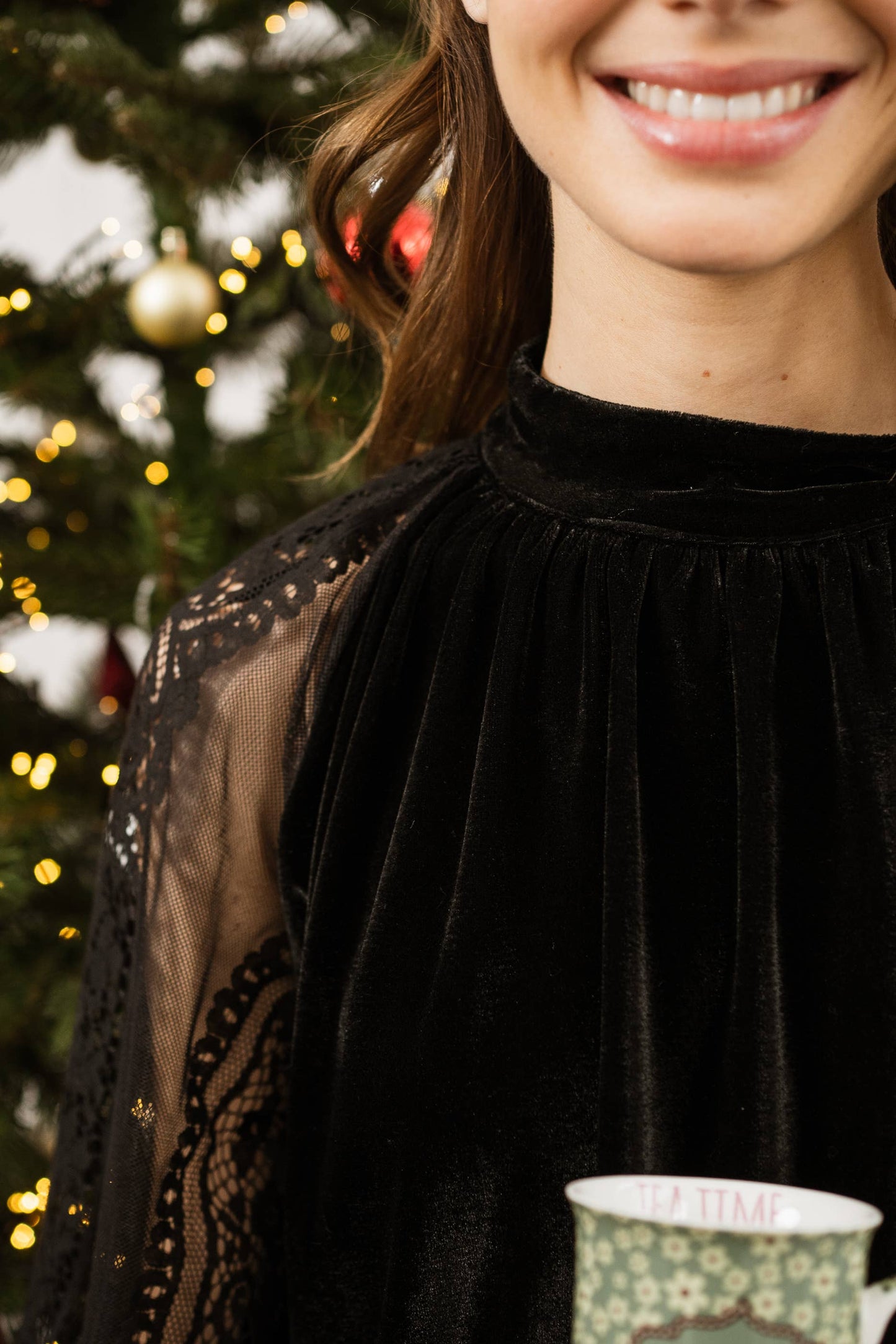 Woman wearing a black velvet top with lace sleeves from Chokolate Paris.