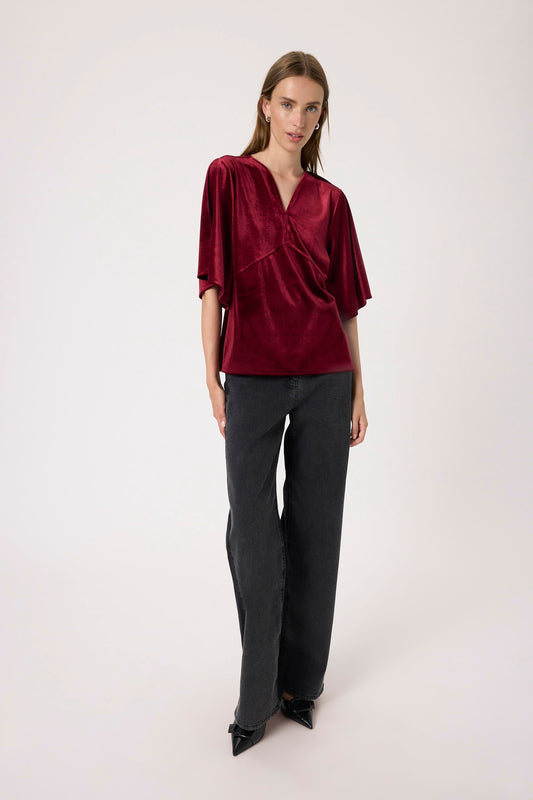 Woman wearing the Soaked in Luxury Velera burgundy velvet top against a white background
