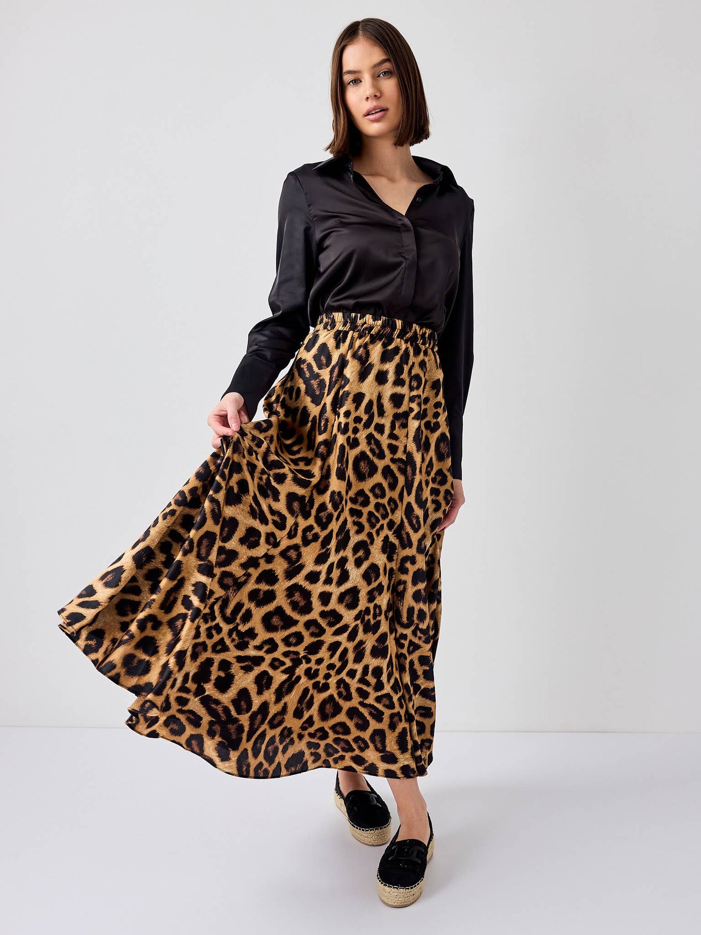 Woman wearing a black shirt and leopard print skirt on a white background