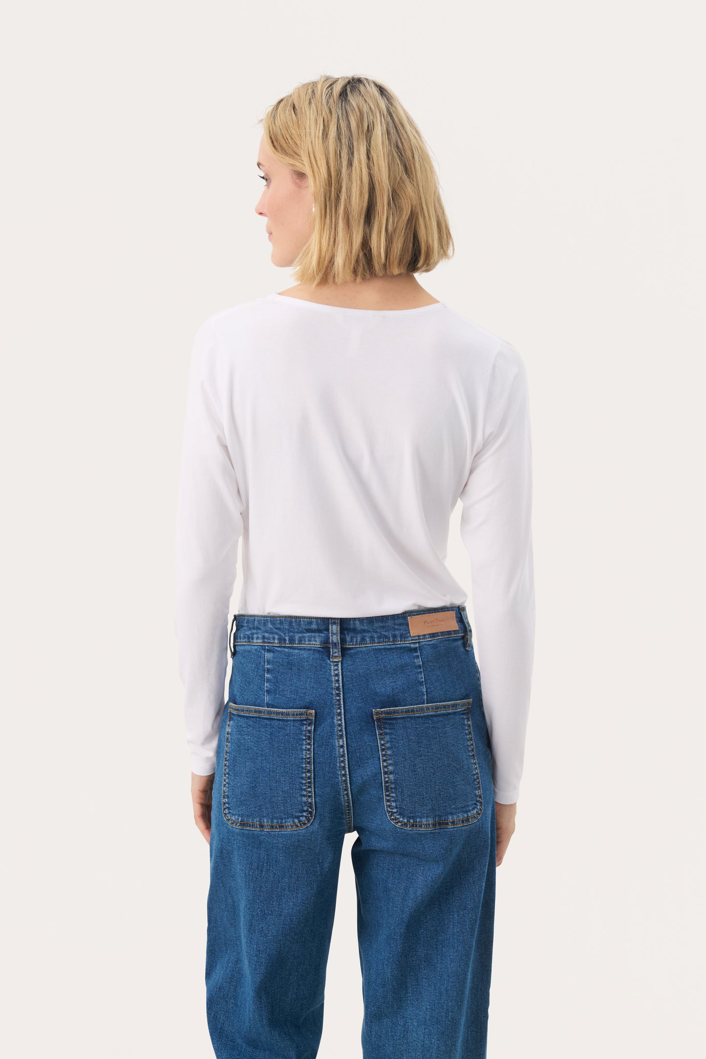 Woman wearing a white long sleeved top and jeans