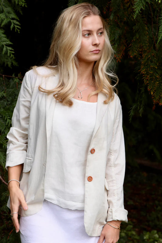 Woman wearing a light-colored cardigan over a white top with a blurred natural background