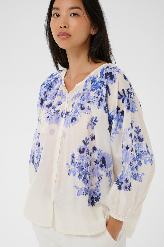 Woman wearing the Part Two Alexi blue floral blouse and white pants on a white background
