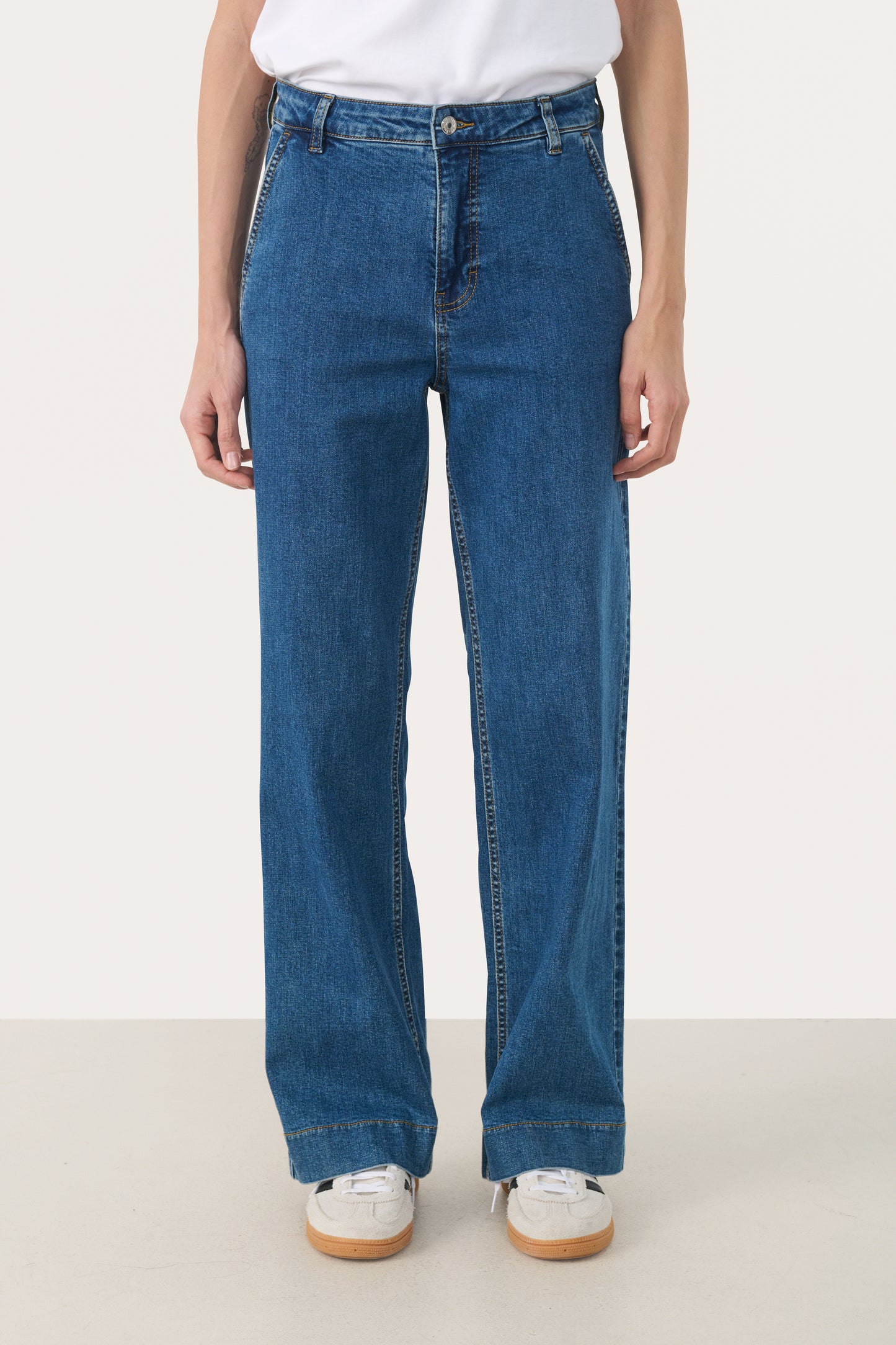 Woman wearing straight leg jeans in a medium blue wash with a white t-shirt
