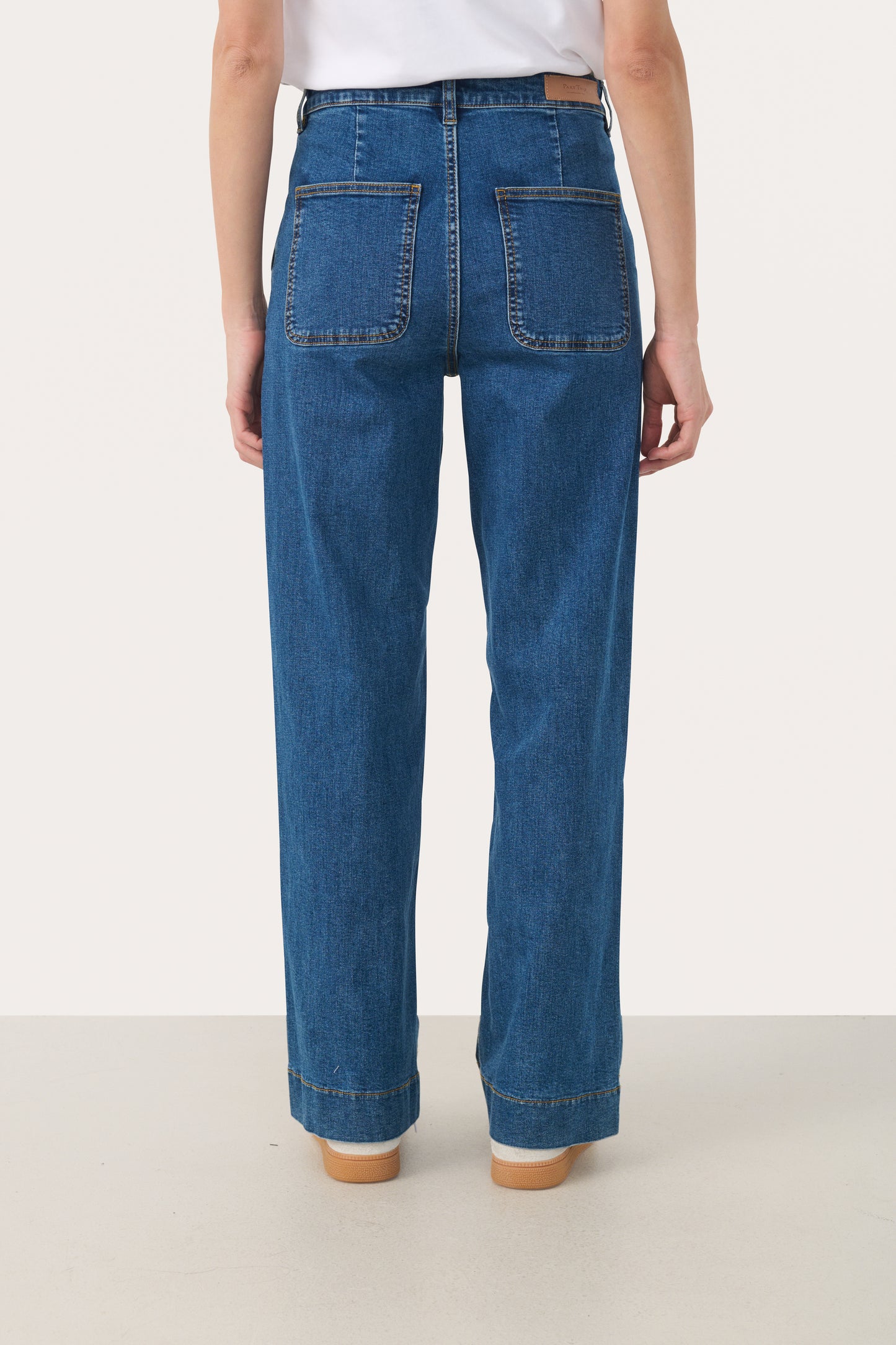 Woman wearing straight leg jeans in a medium blue wash with a white t-shirt. View from the back showing 2 pockets