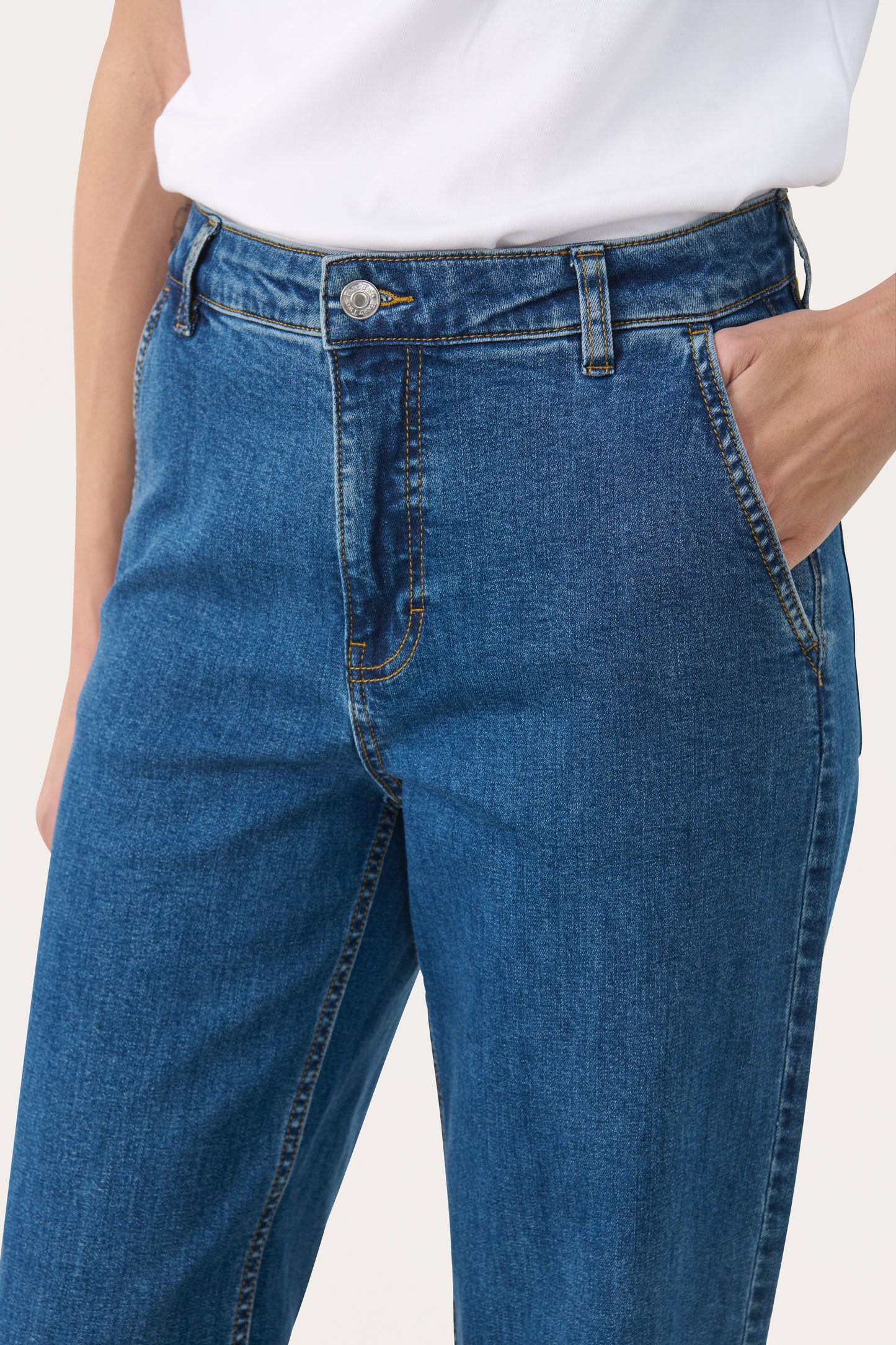 Woman wearing straight leg jeans in a medium blue wash with a white t-shirt