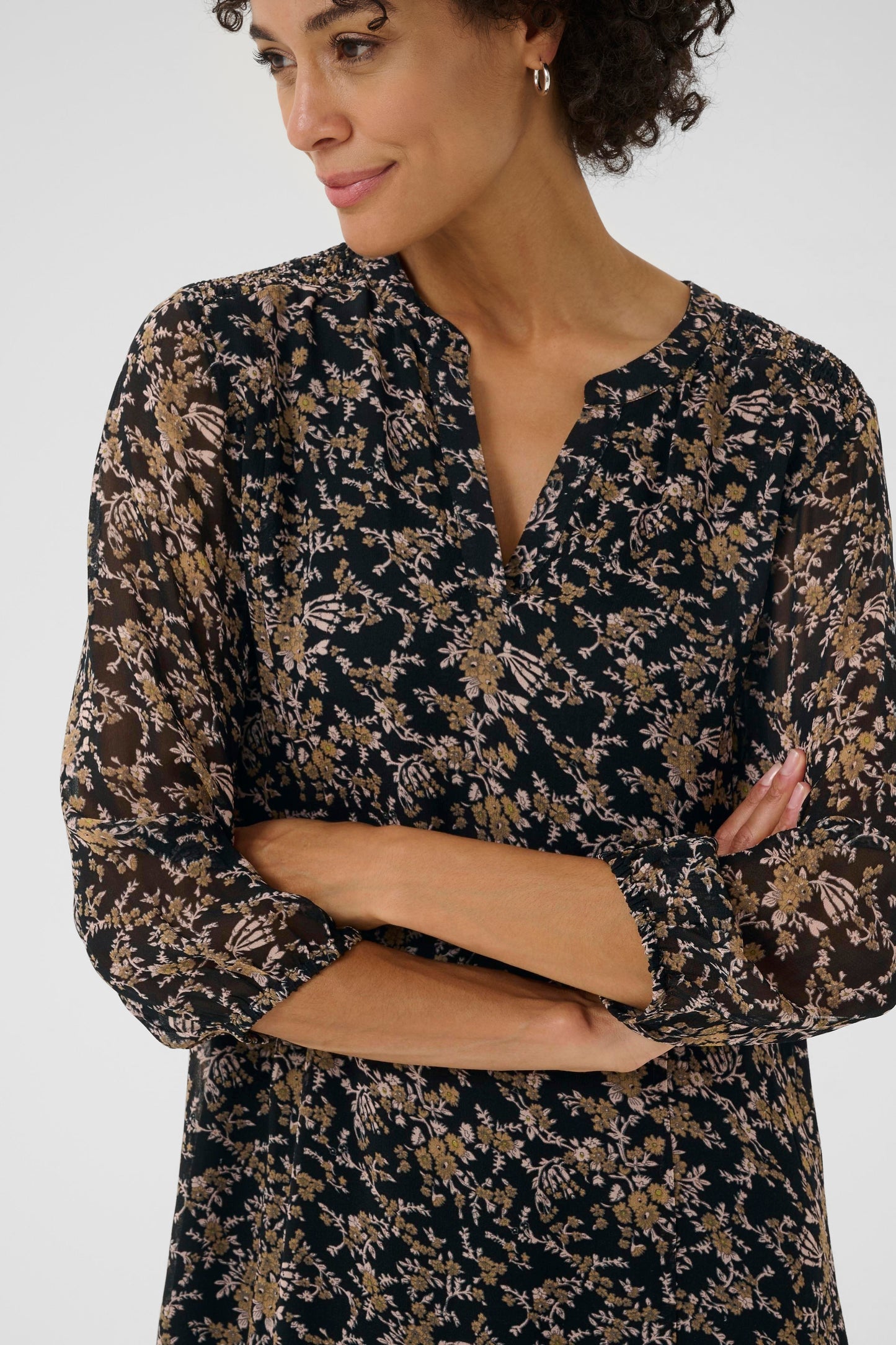 Woman wearing a black floral dress against a white background