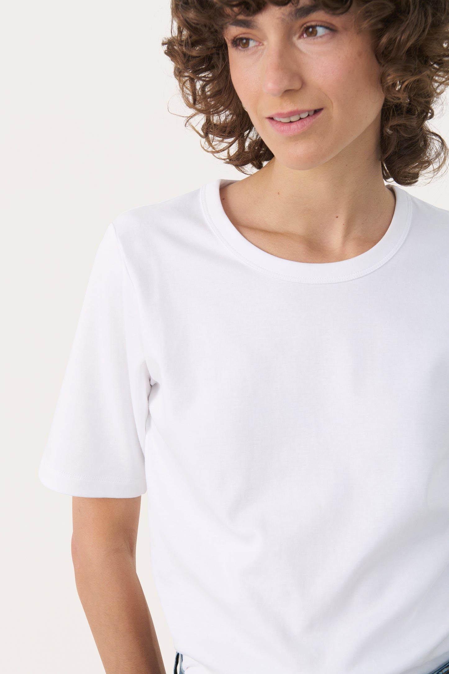 Person wearing the part two ratana white t-shirt and blue jeans on a white background
