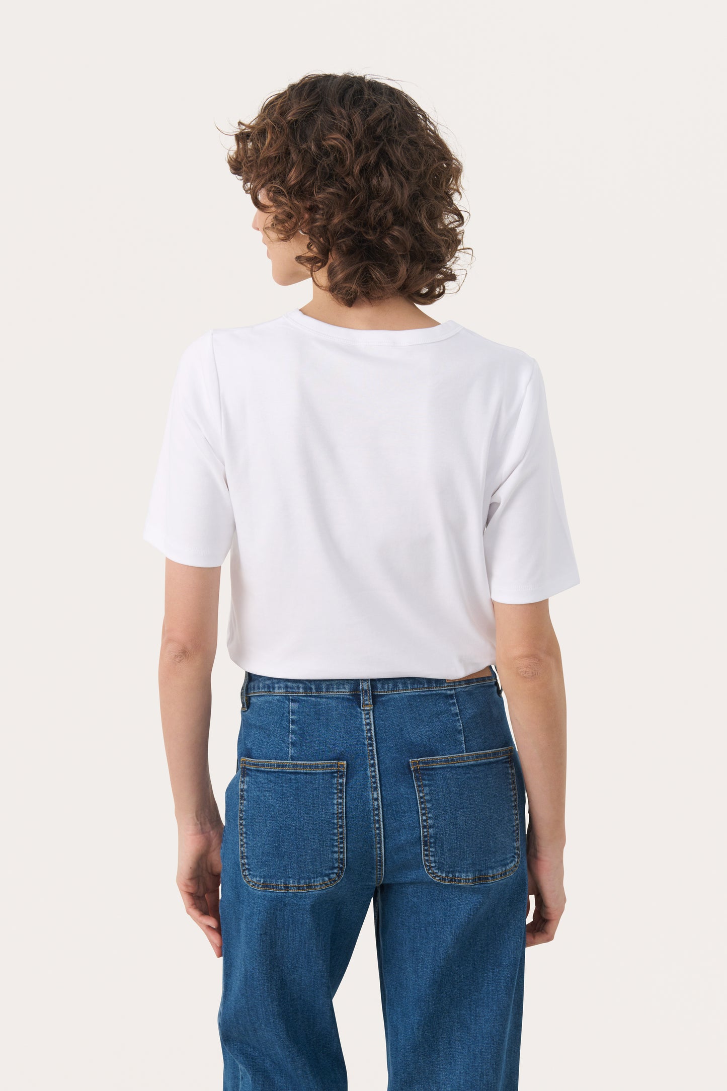 Person wearing the part two ratana white t-shirt and blue jeans on a white background