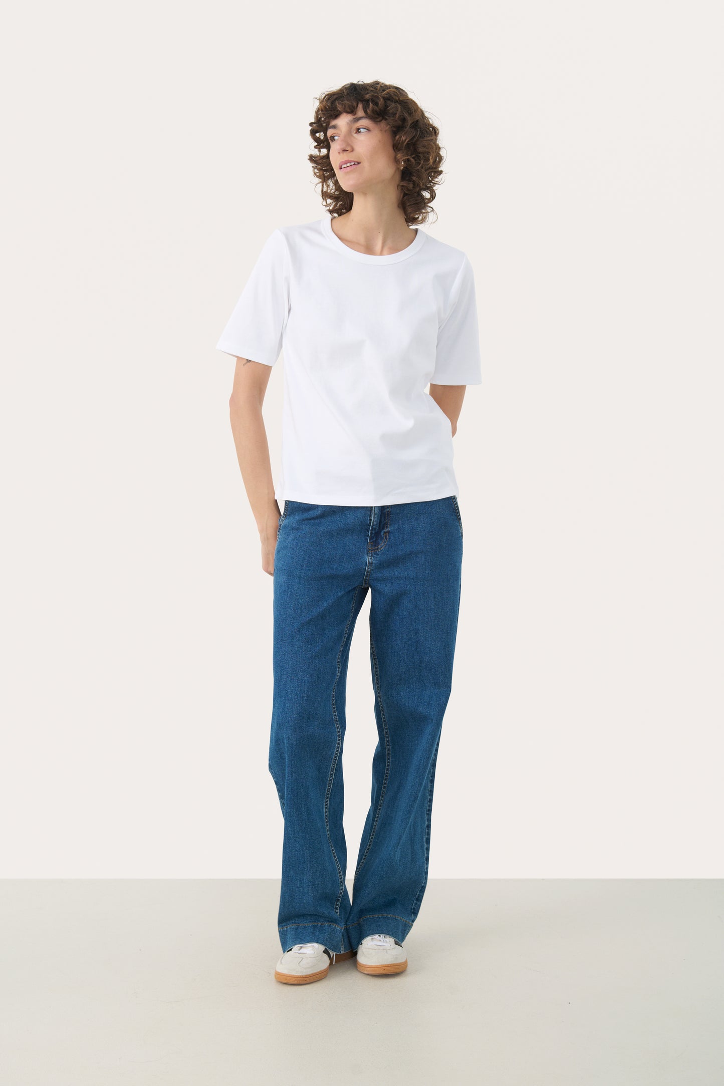 Person wearing the part two ratana white t-shirt and blue jeans on a white background