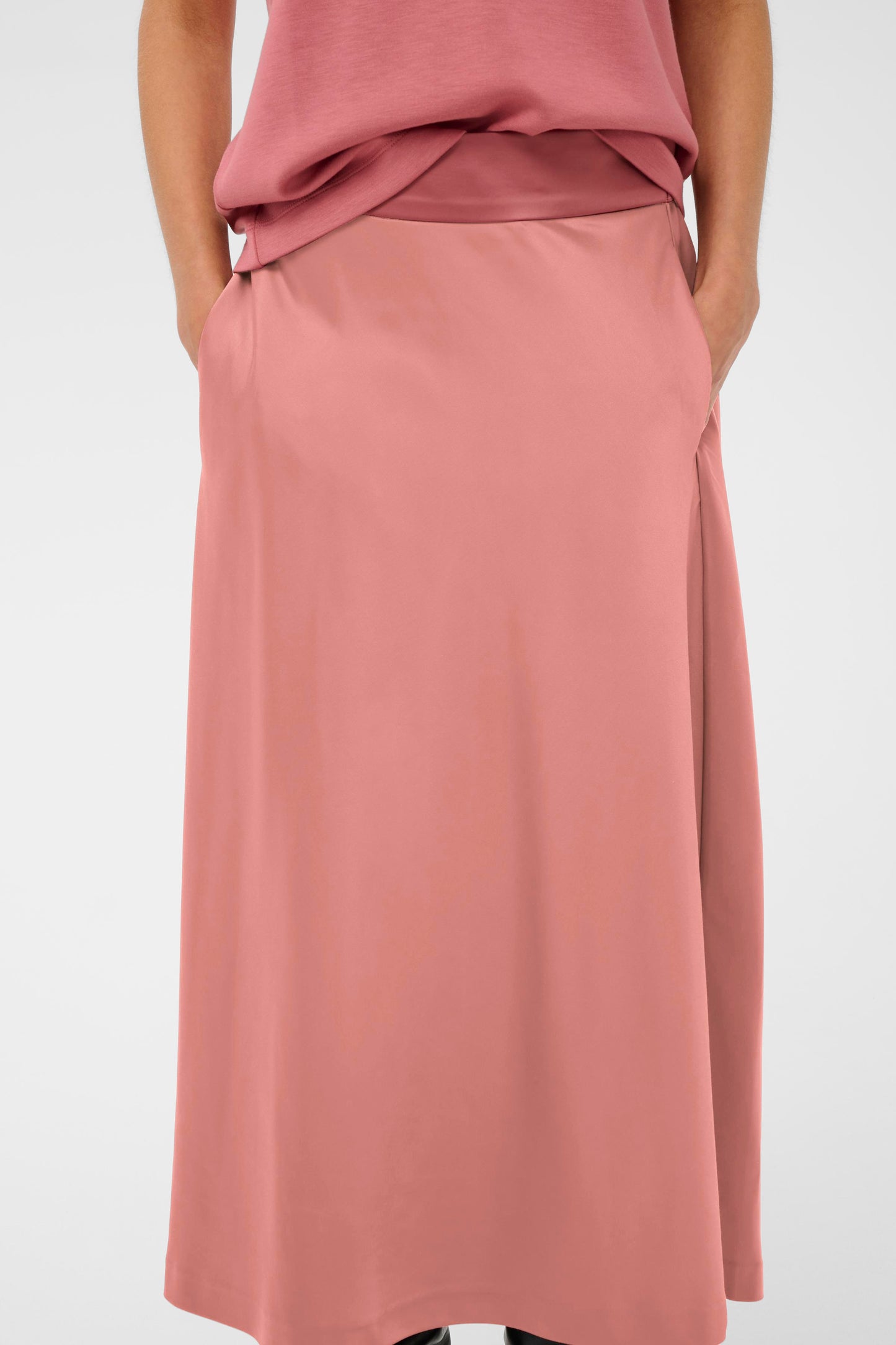 Woman wearing a pink sating skirt and pink Jumper