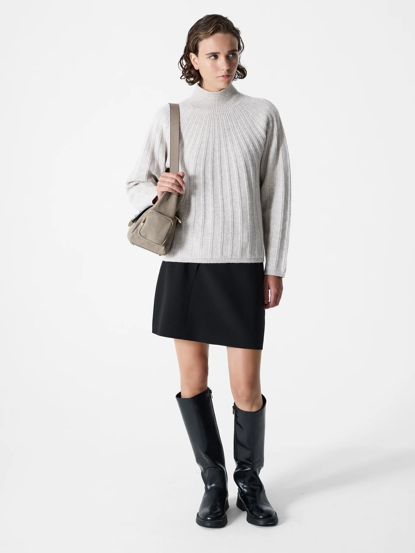 woman wearing a ribbed light colour jumper with a mock neck. Long sleeves