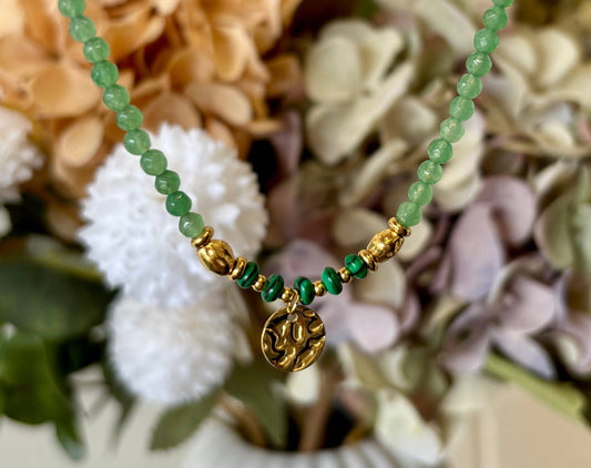 bracelet with green beads and gold charm on a floral background