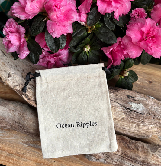 Small pouch labeled 'Ocean Ripples' with pink flowers in the background on a wooden surface