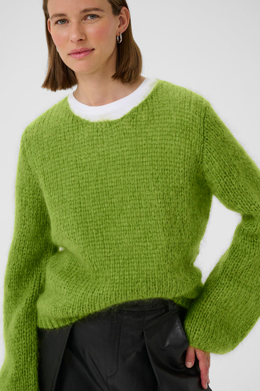 Woman wearing a green mohair jumper on a white background