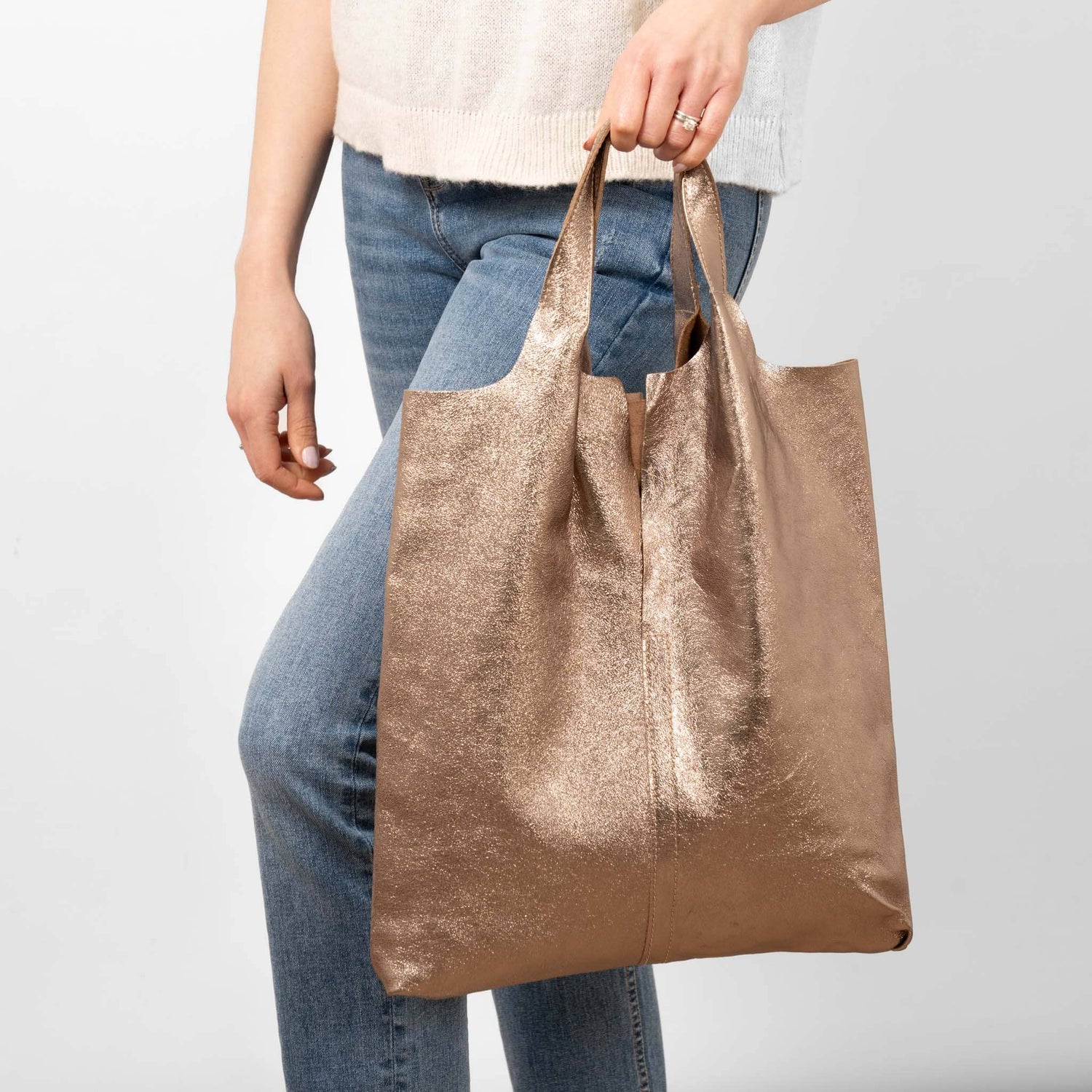 Woman holding a metallic rose gold tote bag