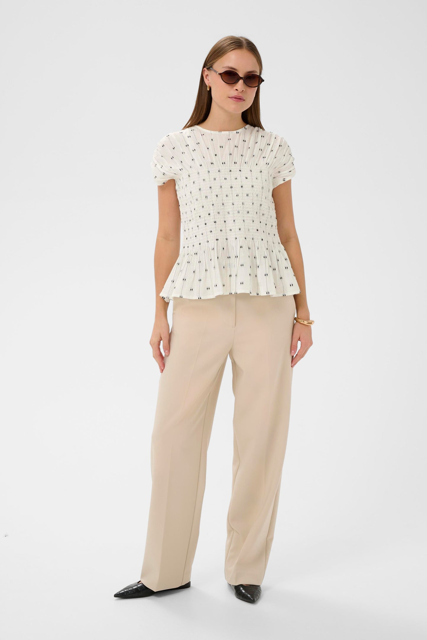 Woman wearing the Soaked in Luxury Amelie white blouse with black dots  and  ruffled details.