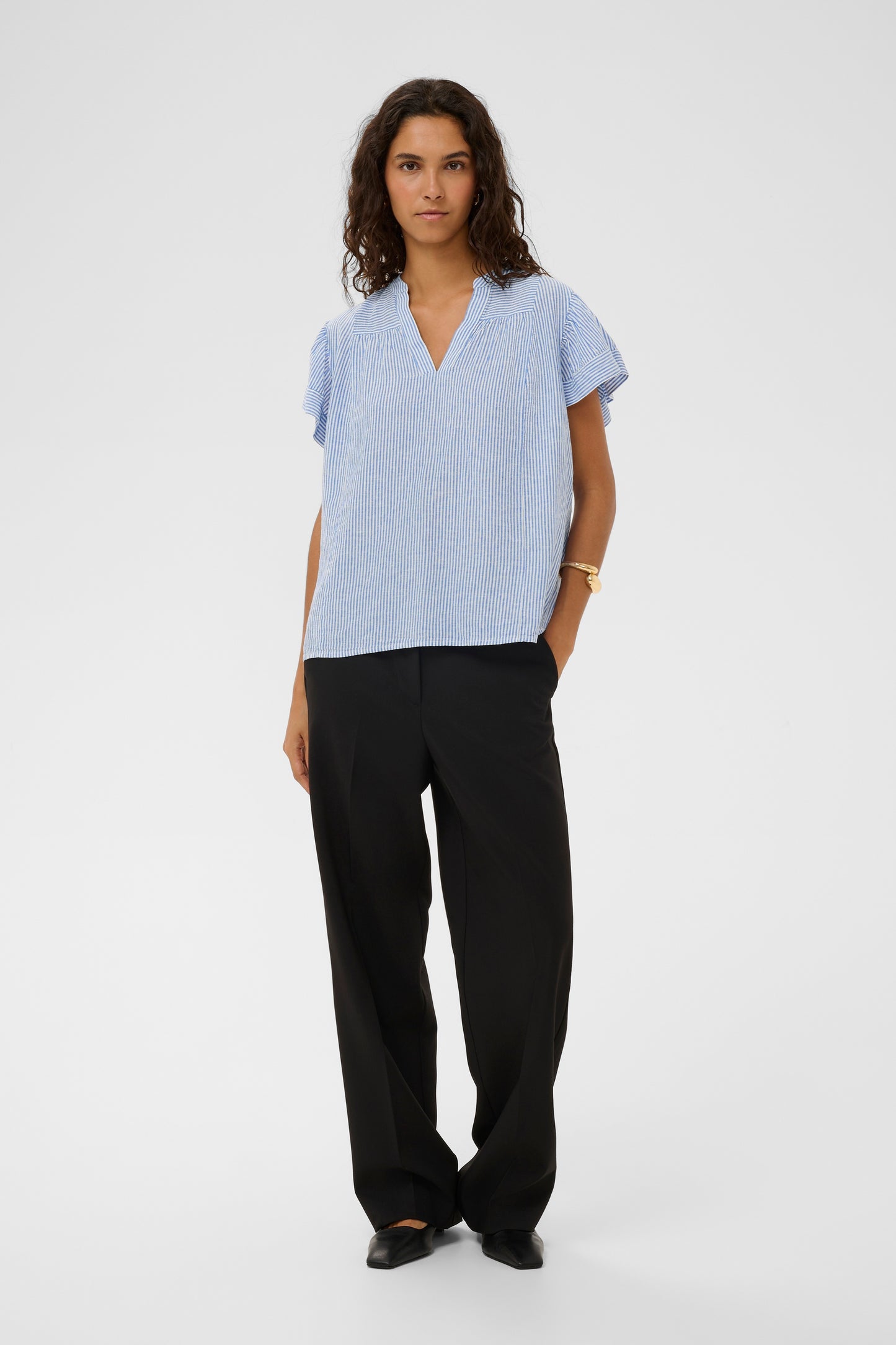 Woman wearing the Aria Blouse in light blue with white stripes