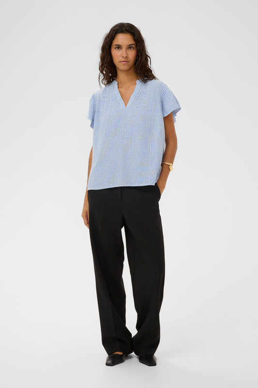 Woman wearing the Aria Blouse in light blue with white stripes