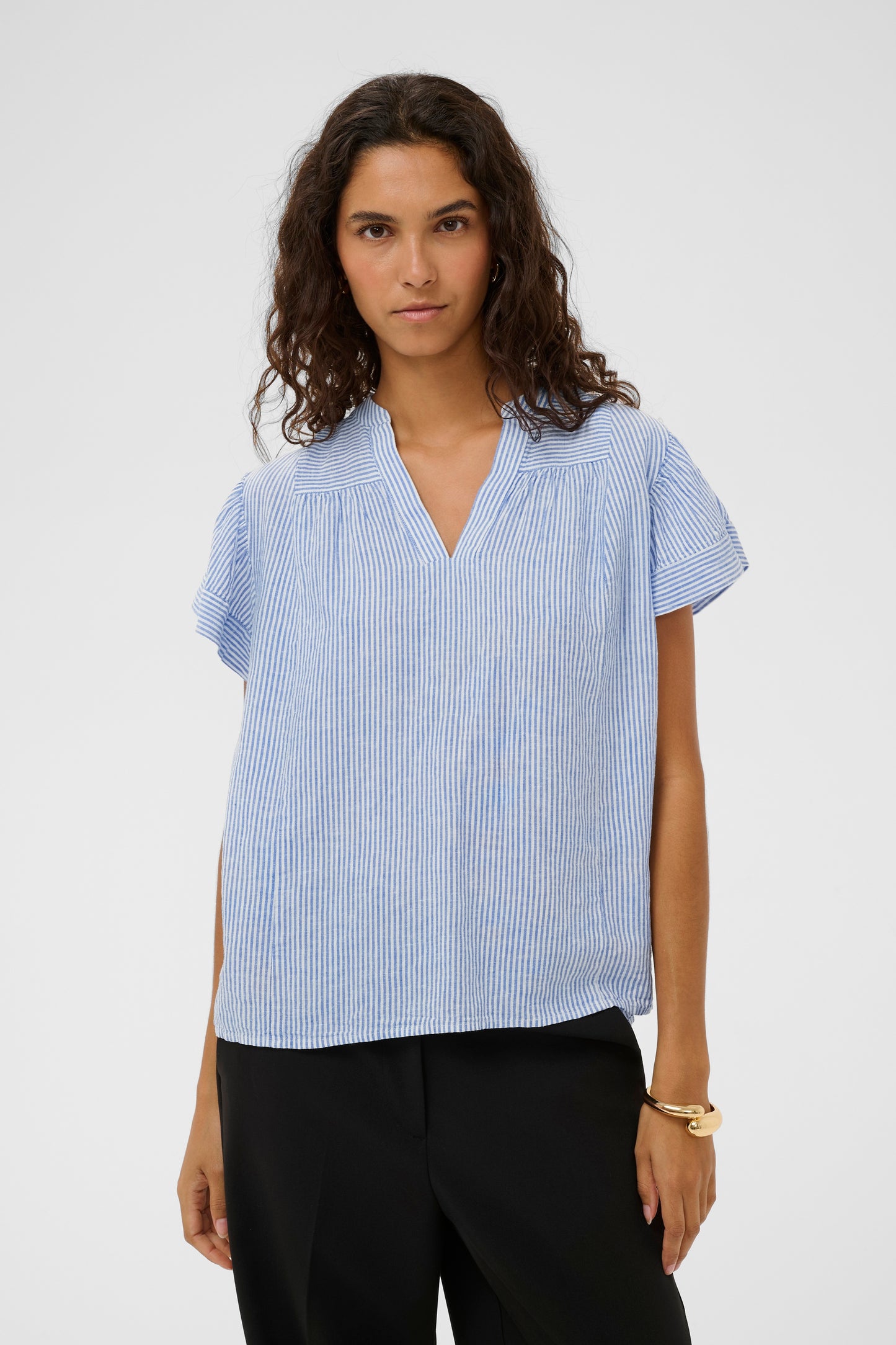 Woman wearing the Aria Blouse in light blue with white stripes