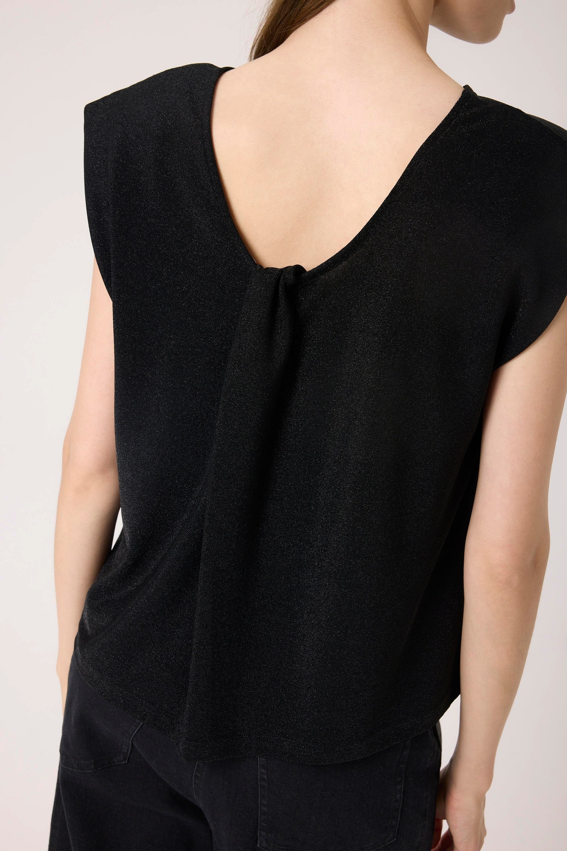 Woman wearing the Soaked in Luxury Skylara Tank top in black with metallic yarn  View from back of soft scoop back