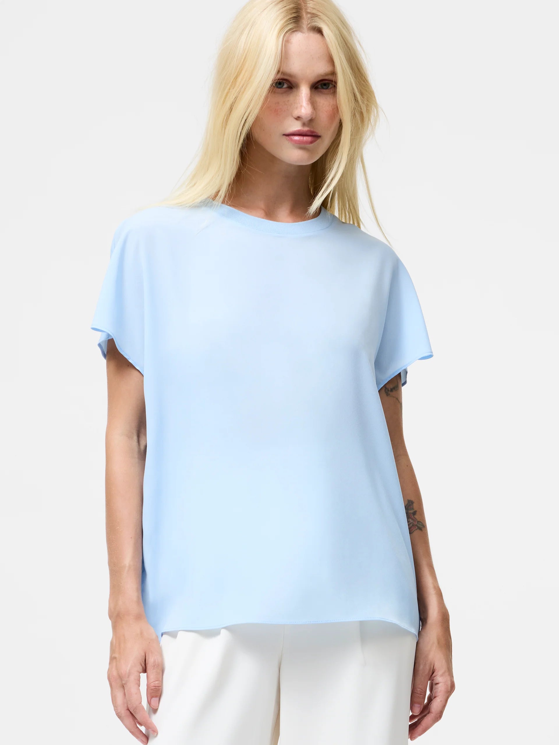 Woman wearing a light blue top with short sleeves and crew neck