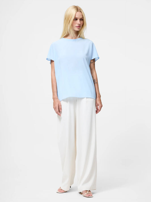 Woman wearing a light blue top with short sleeves and crew neck