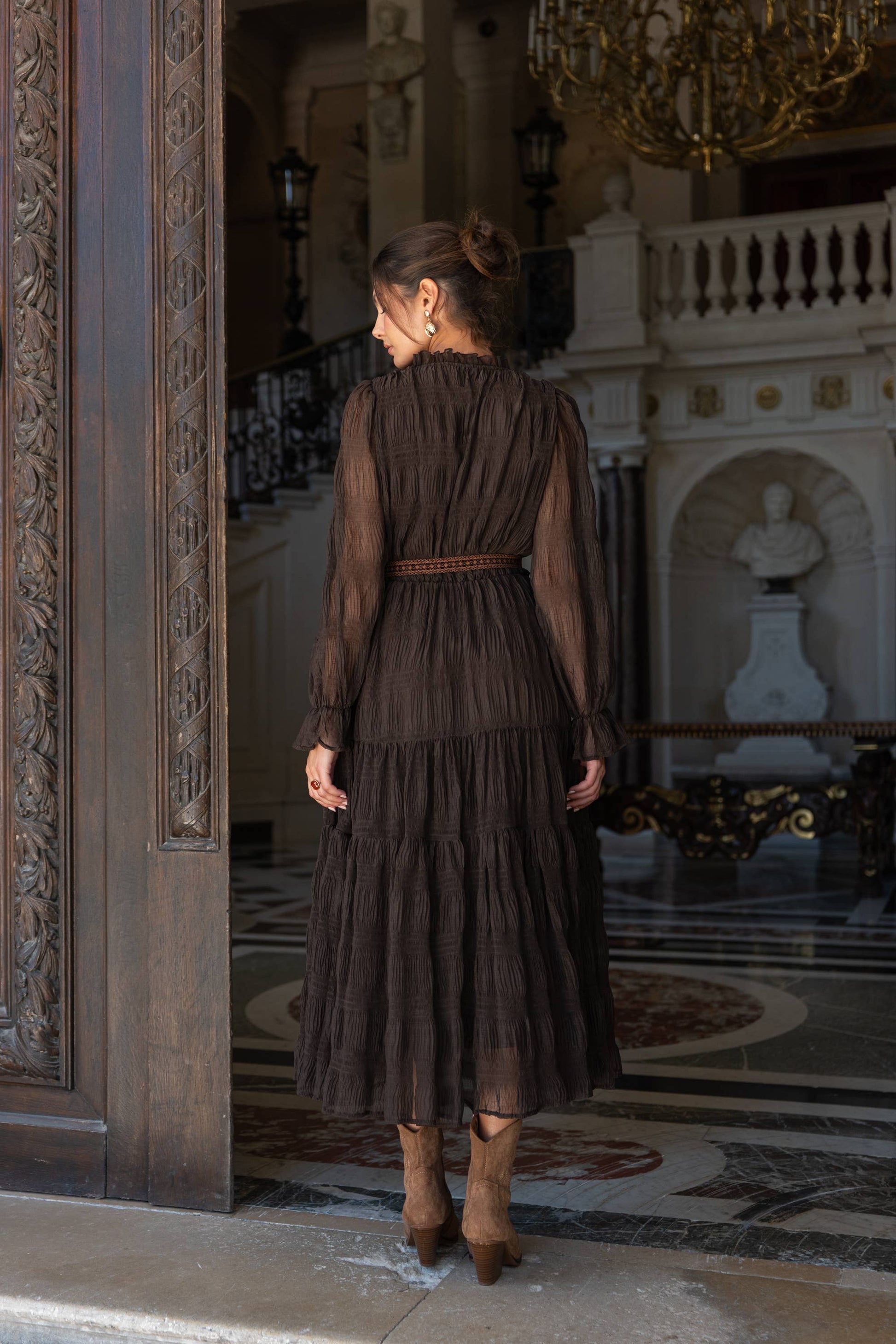 Woman wearing a long ruched brown dress with long chiffon sleeves
