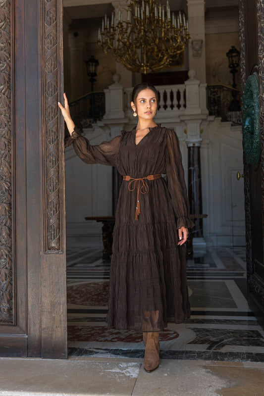 Woman wearing a long ruched brown dress with long chiffon sleeves