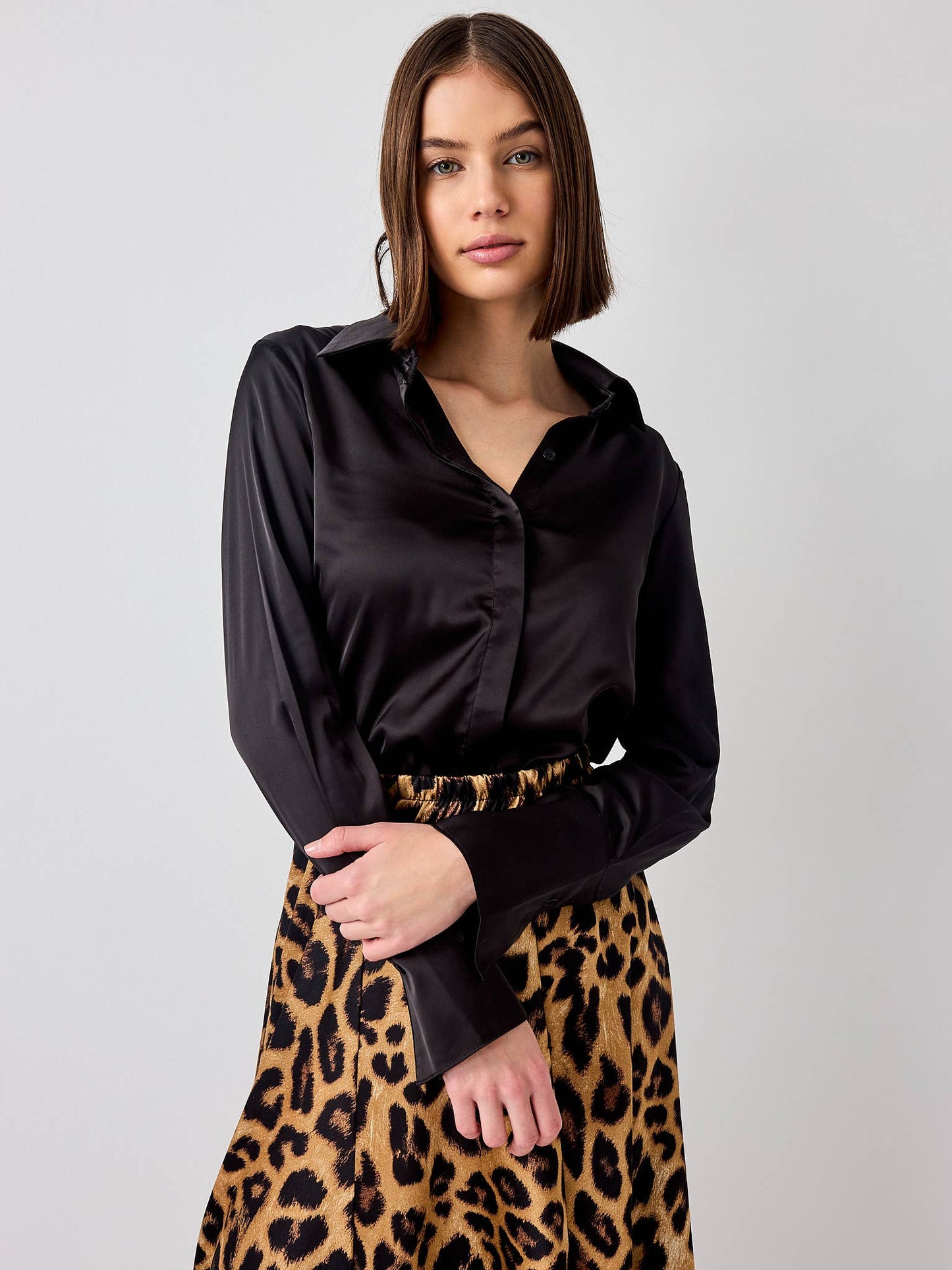 Woman wearing a black blouse and leopard print skirt on a plain background