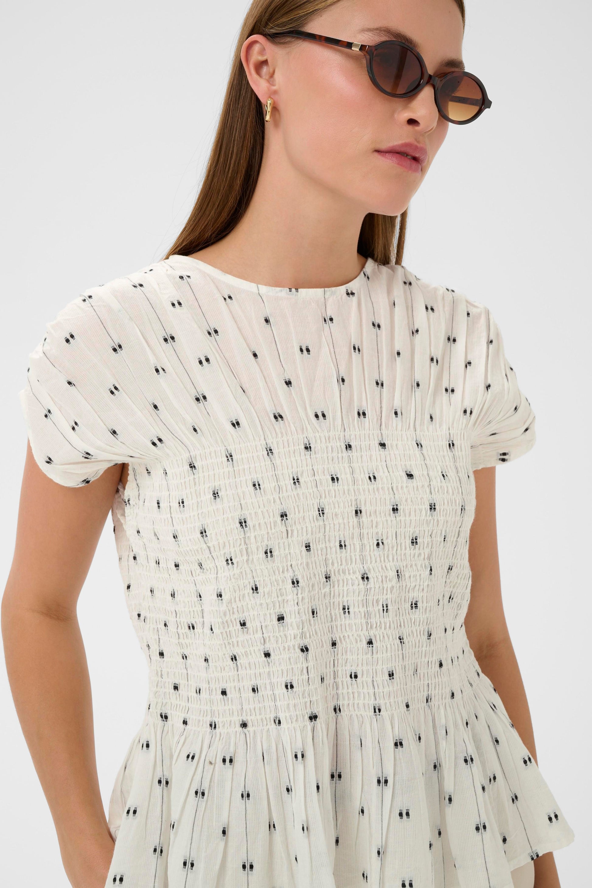 Woman wearing the Soaked in Luxury Amelie white blouse with black dots  and  ruffled details.