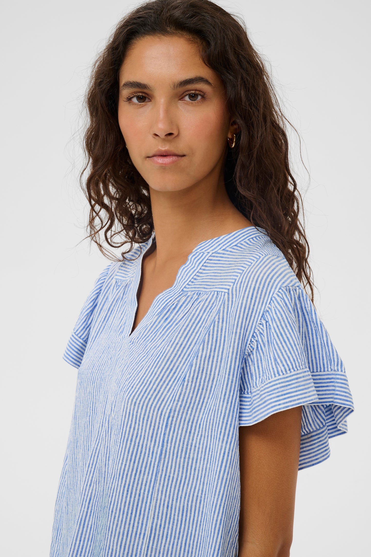 Woman wearing the Aria Blouse in light blue with white stripes