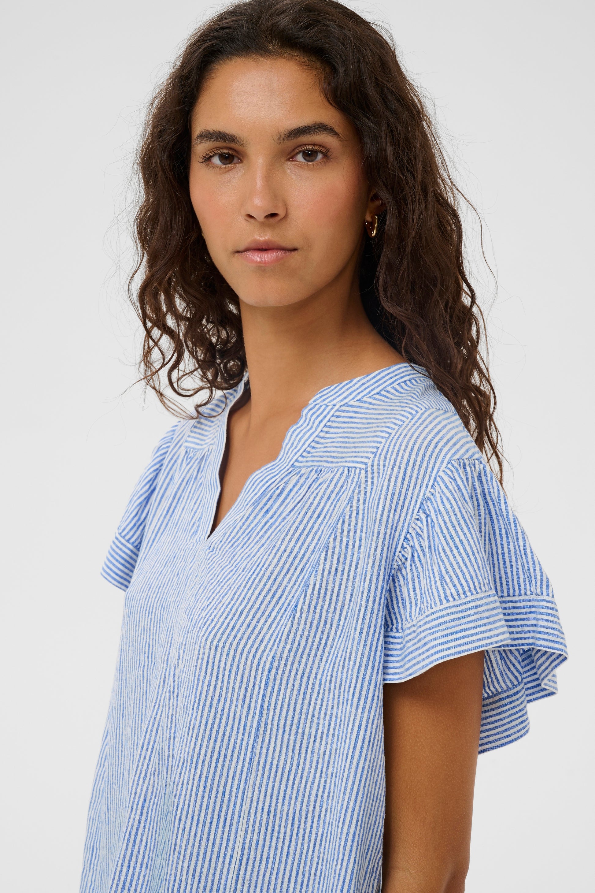 Woman wearing the Aria Blouse in light blue with white stripes