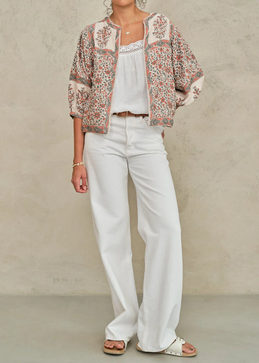 Woman wearing a floral jacket, white top, and pants against a neutral background