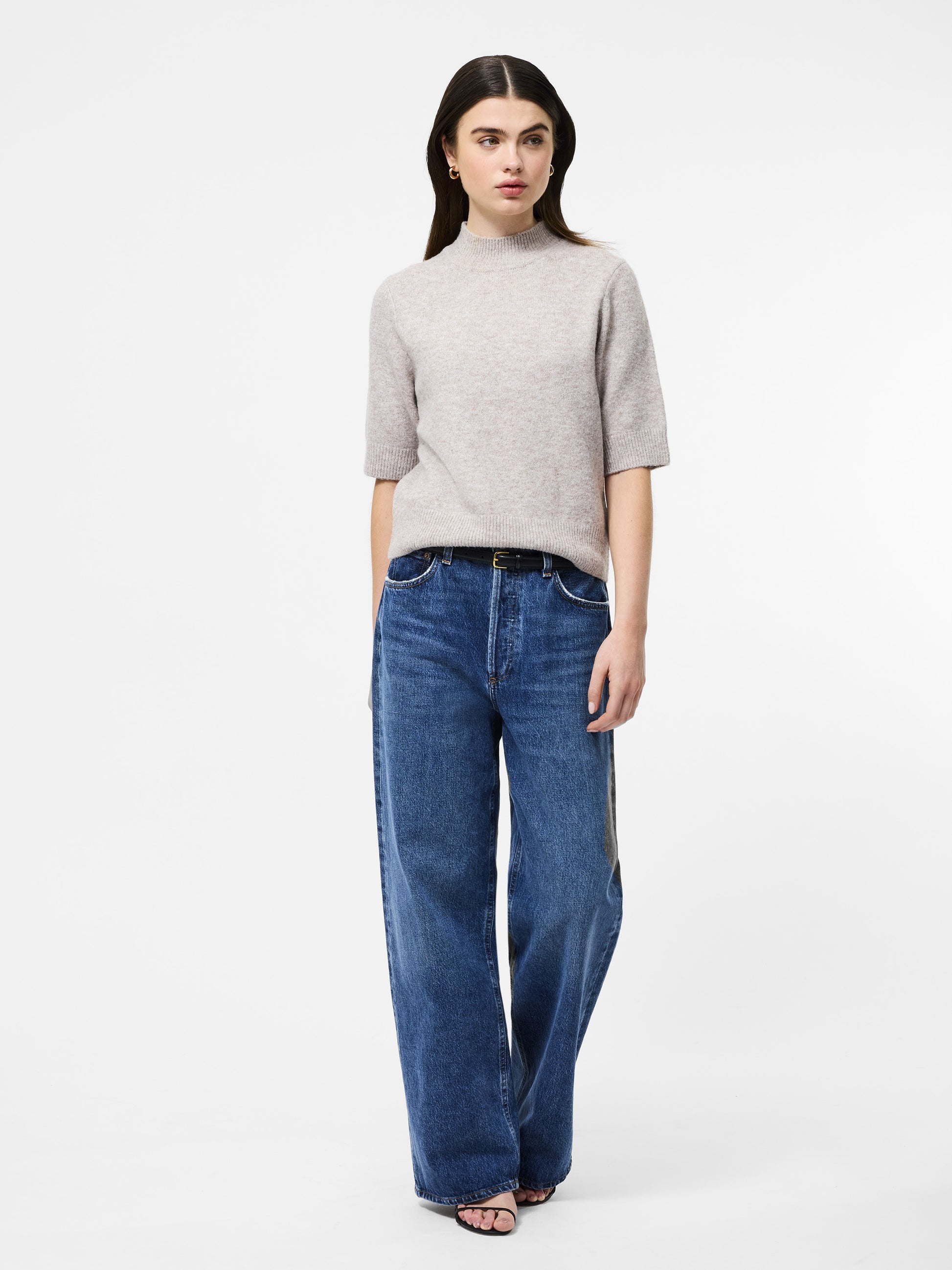 
Woman wearing a mock neck almond coloured short sleeved jumper 