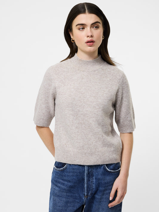 Woman wearing a mock neck almond coloured short sleeved jumper