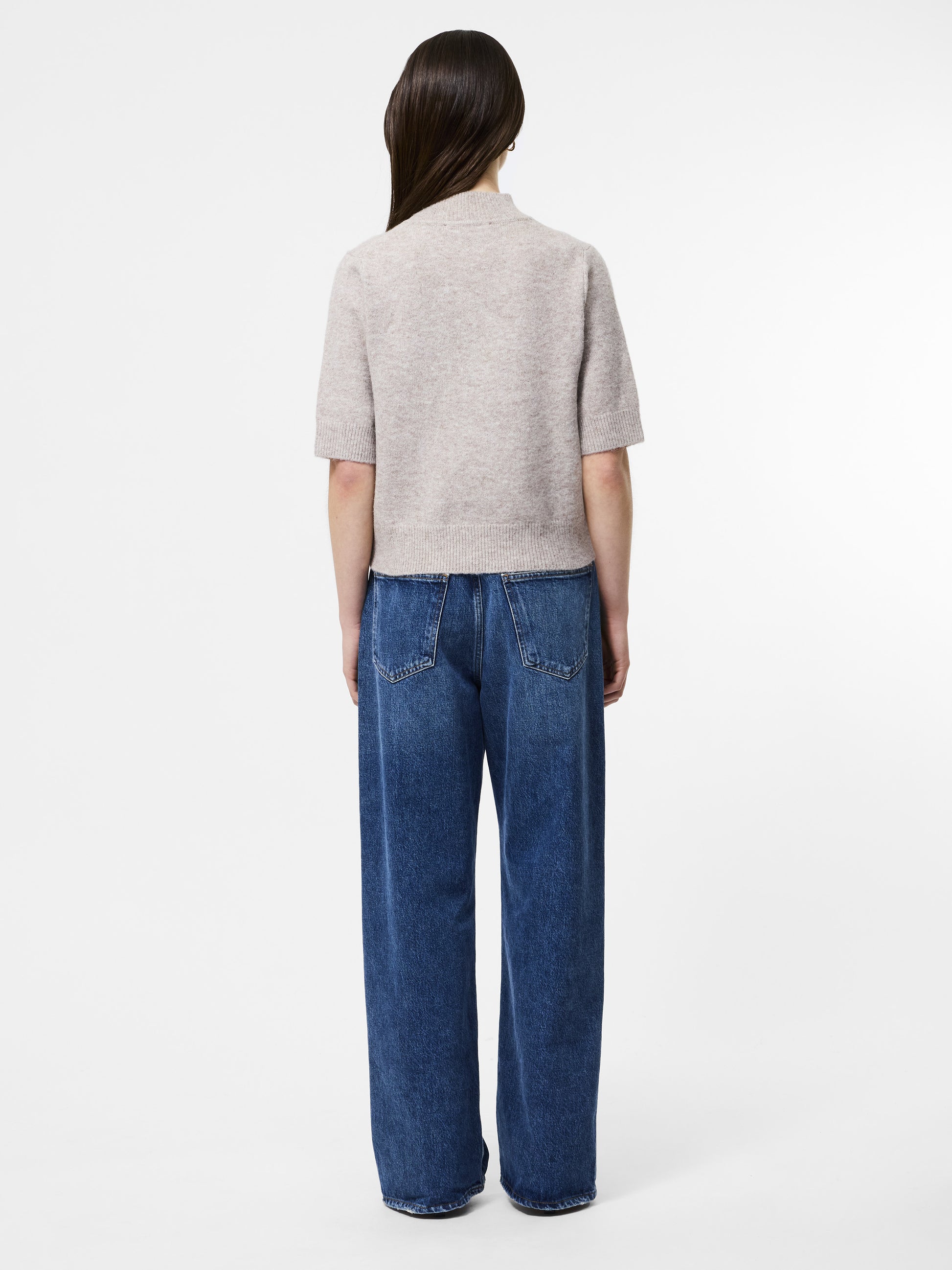 Woman wearing a mock neck almond coloured short sleeved jumper 