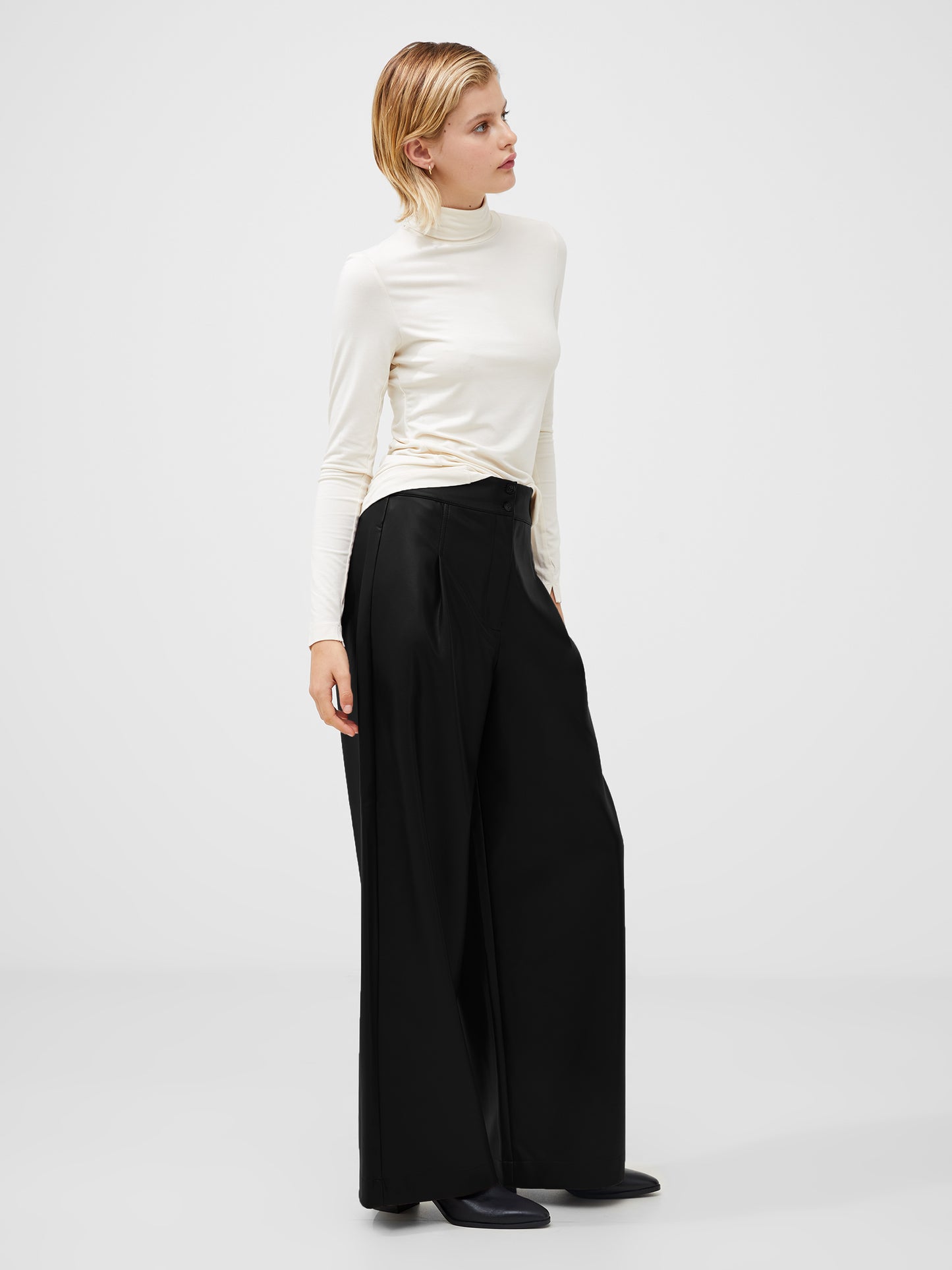 
Woman Wearing a cream polo neck top with splits in the cuff
