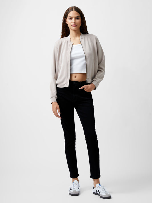 Woman wearing a cropped khaki colour zip up bomber jacket.  She is wearing a pair of black jeans too.