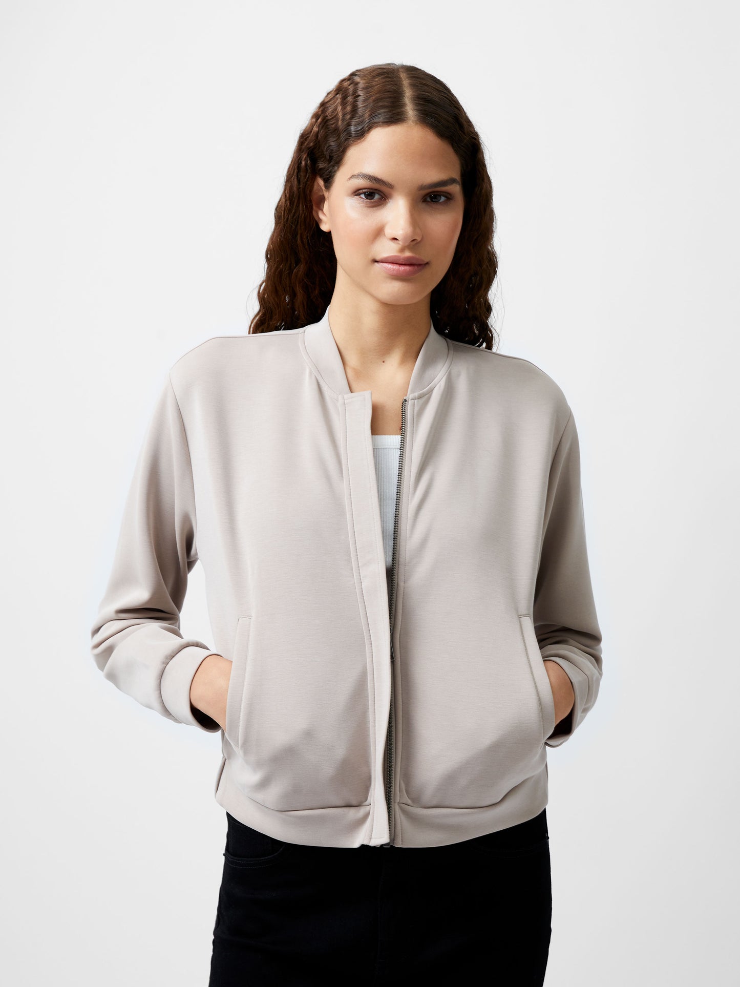 Woman wearing a cropped khaki colour zip up bomber jacket.  She is wearing a pair of black jeans too.