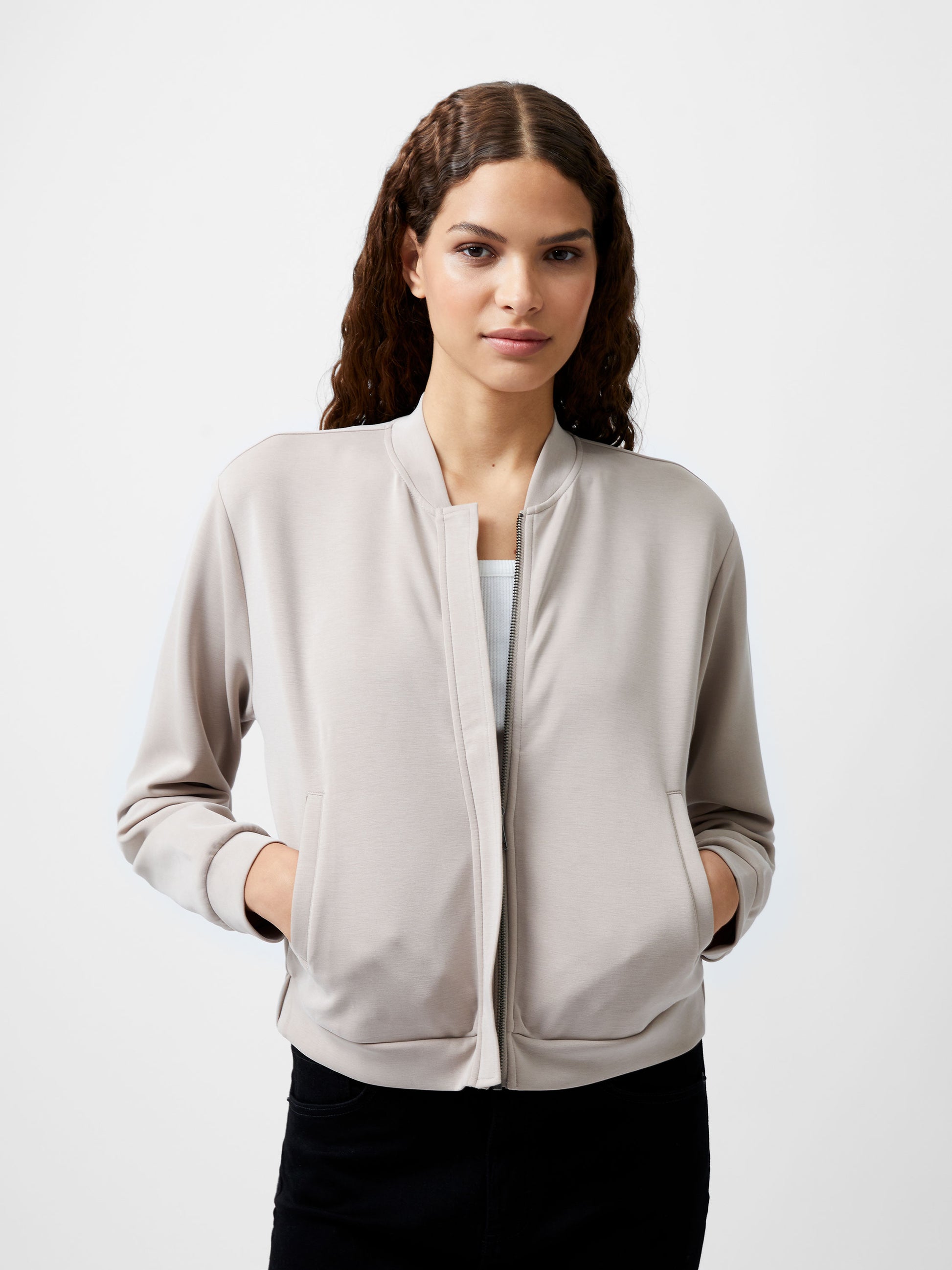 Woman wearing a cropped khaki colour zip up bomber jacket.  She is wearing a pair of black jeans too.