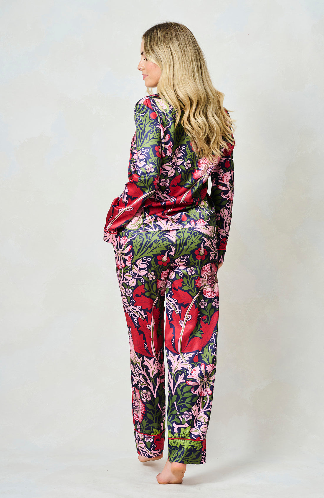 Woman wearing the floral  Marianna satin pyjamas by Hope and Ivy.  In blue, green and pink colours