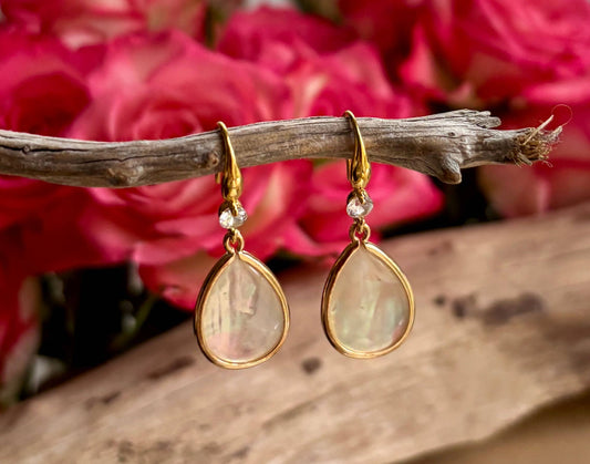 Gold teardrop earrings with mother of pearl on a branch with pink flowers in the background
