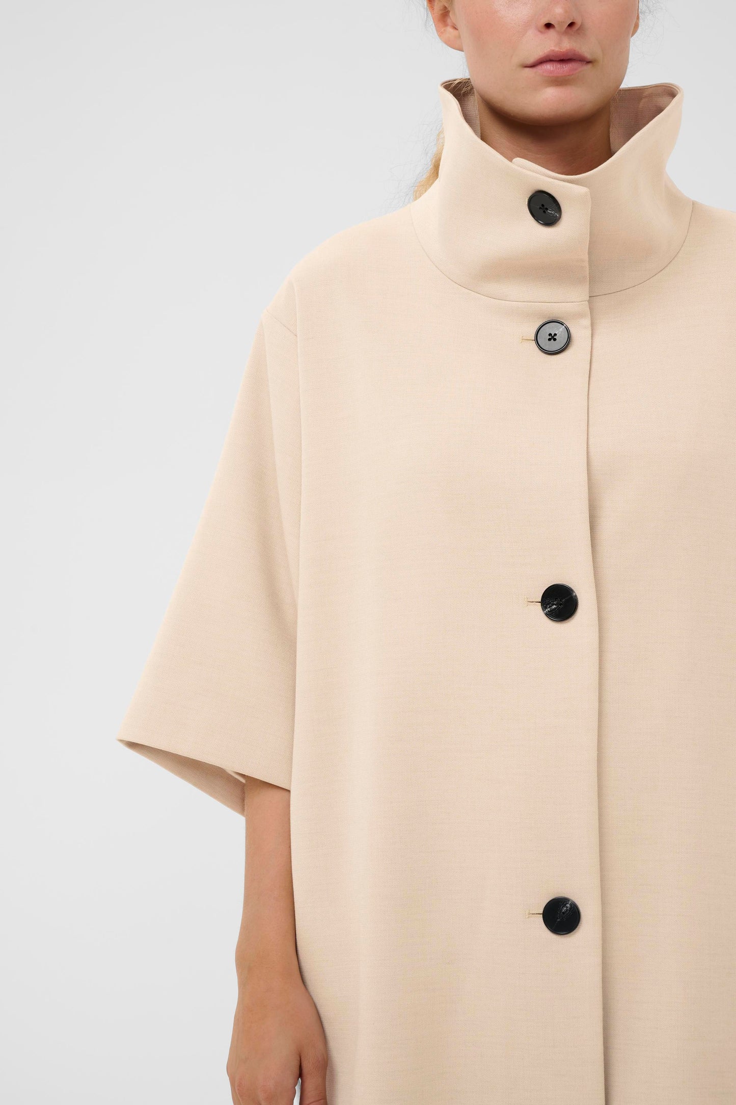 Woman wearing the InWear HollyN beige cape with black buttons on a white background