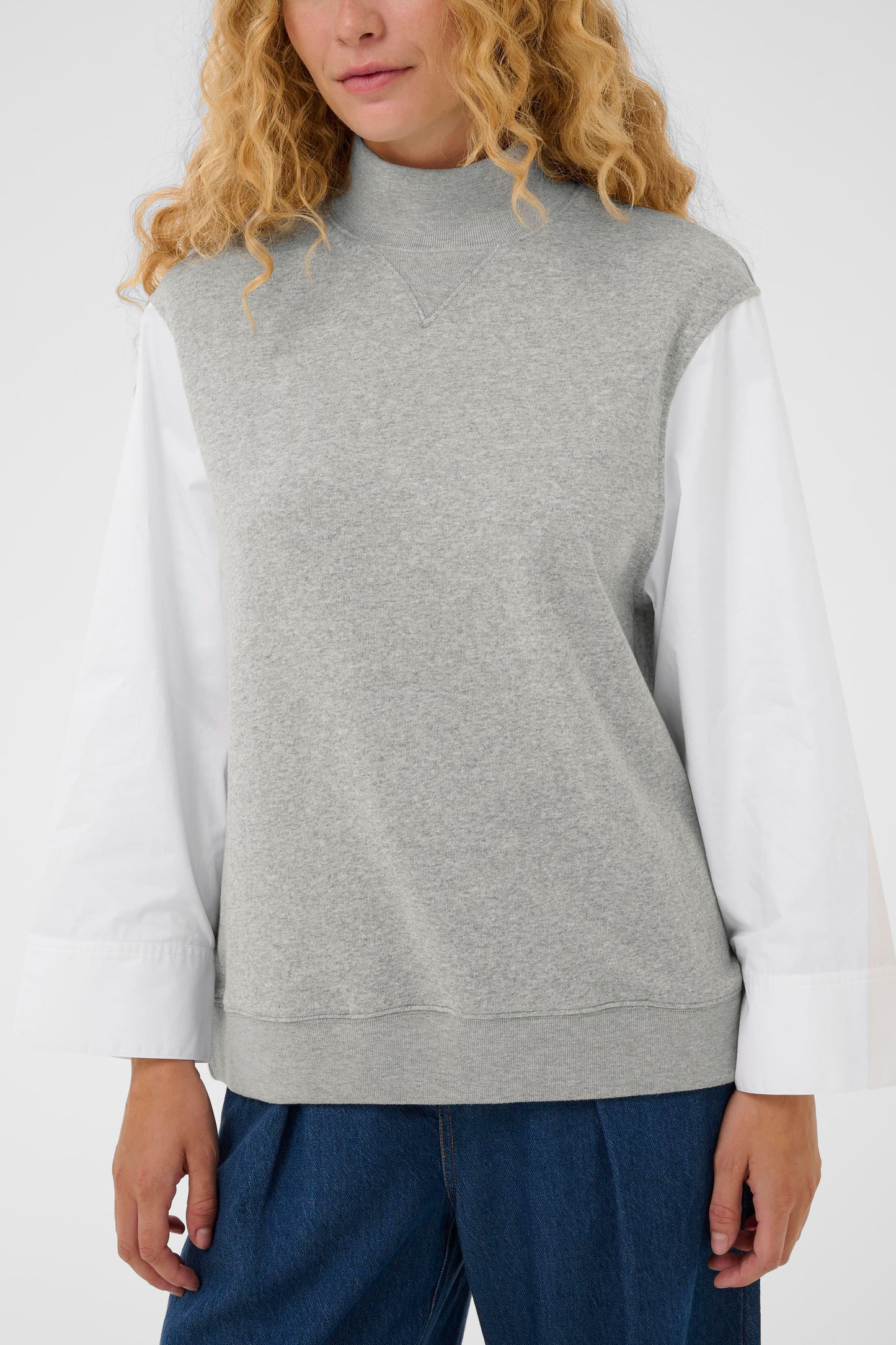 Woman wearing the InWear Capella light grey sleeveless sweater with white shirt sleeves.  All in one piece.