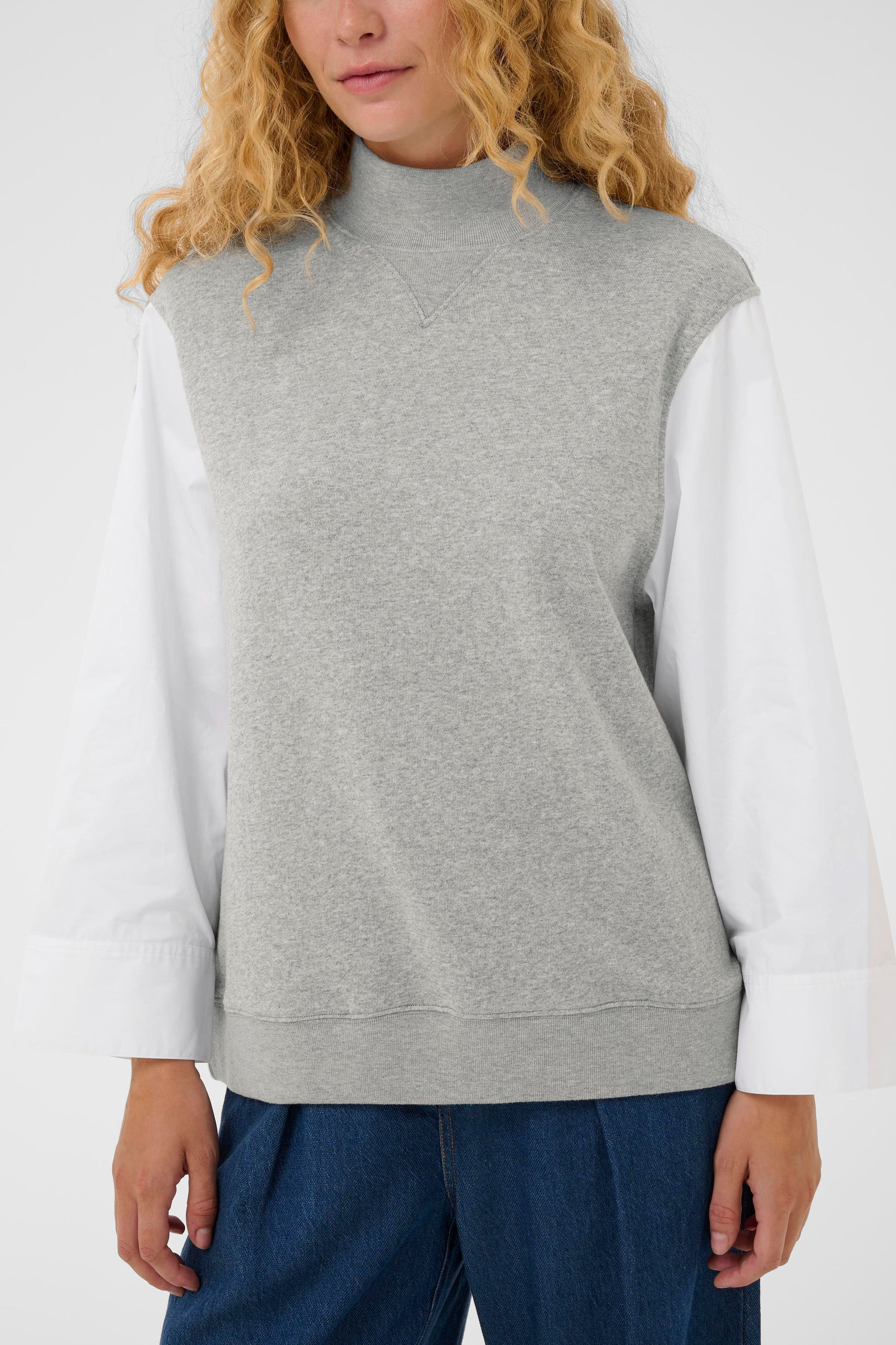 Woman wearing the InWear Capella light grey sleeveless sweater with white shirt sleeves.  All in one piece.
