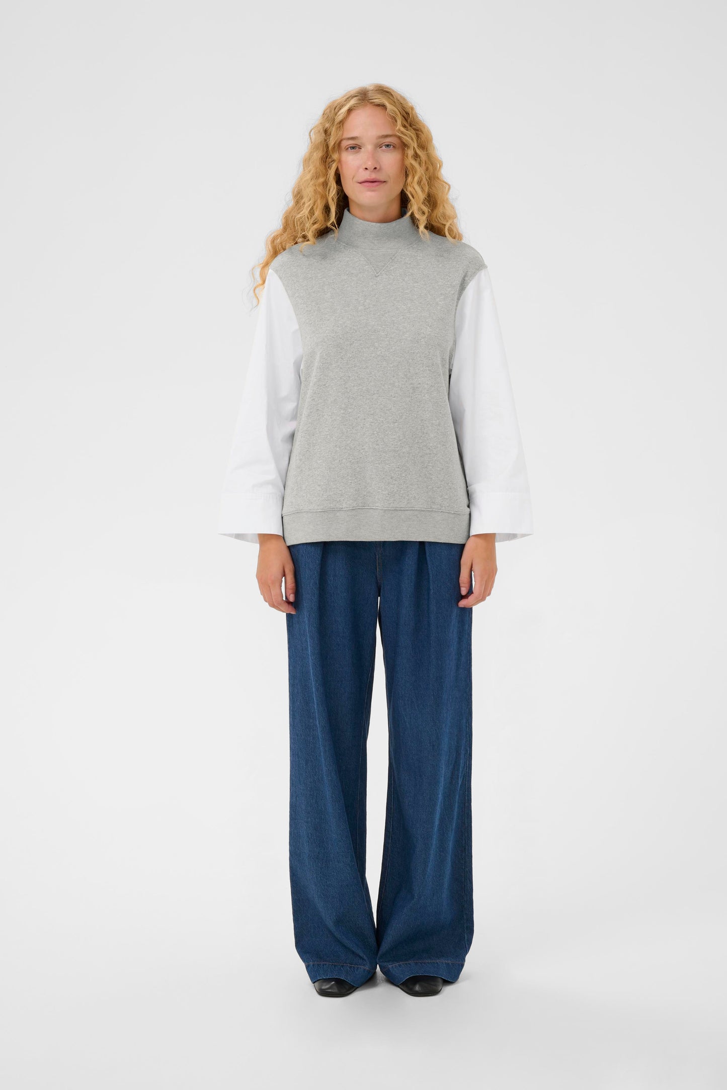 Woman wearing the InWear Capella light grey sleeveless sweater with white shirt sleeves.  All in one piece.