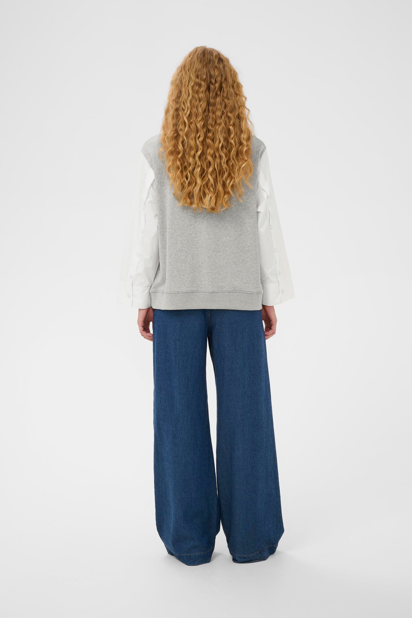 Woman wearing the InWear Capella light grey sleeveless sweater with white shirt sleeves.  All in one piece.