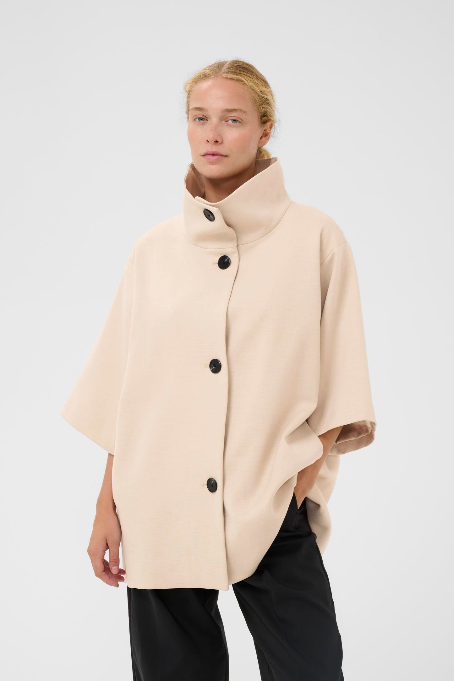 Woman wearing the InWear HollyN beige cape with black buttons on a white background