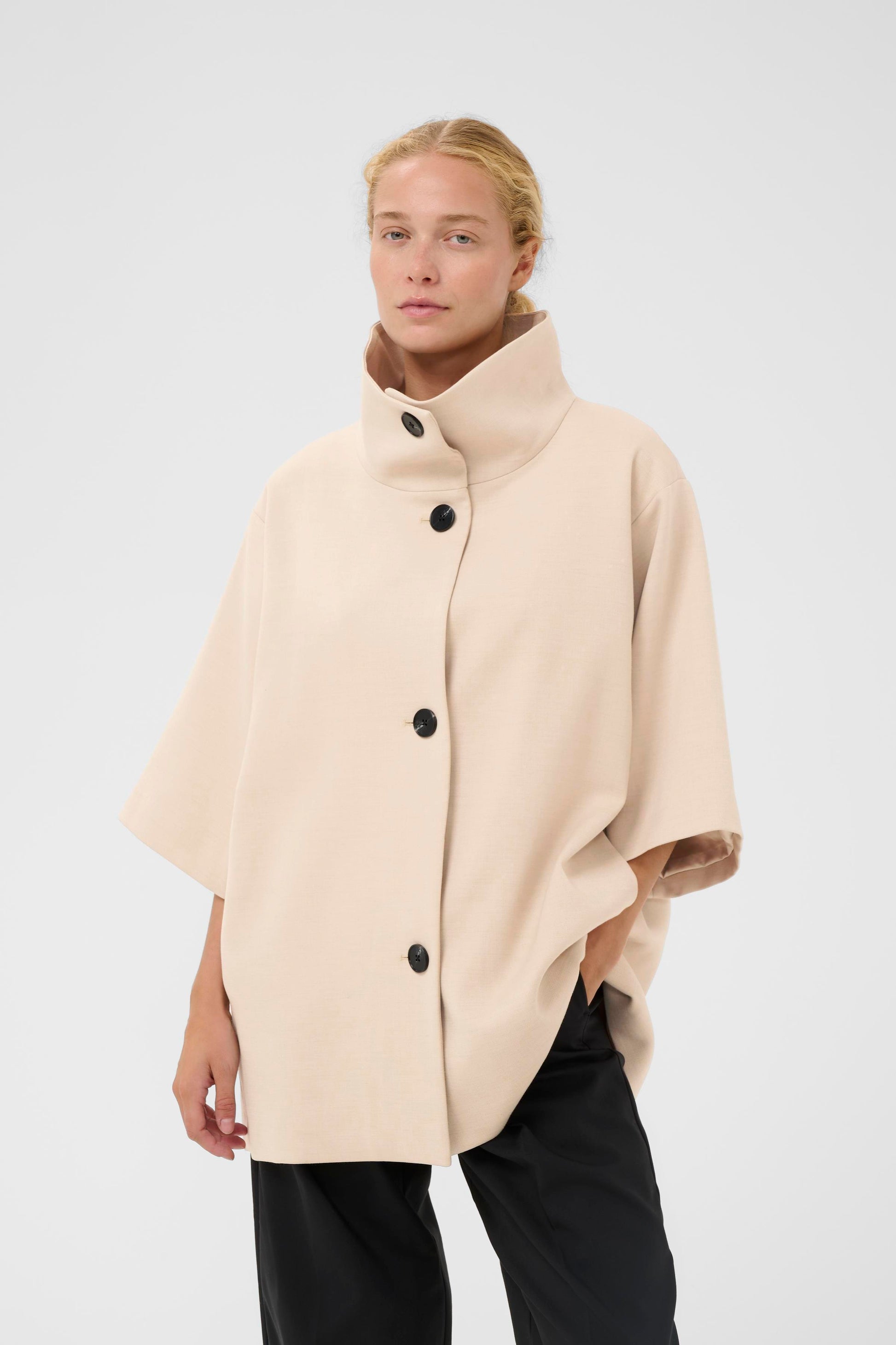 Woman wearing the InWear HollyN beige cape with black buttons on a white background